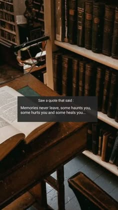 an open book sitting on top of a wooden table in front of bookshelves