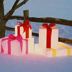 three boxes with bows are sitting in the snow next to a tree and fence on a snowy day