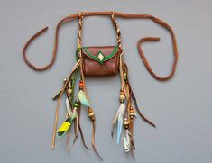 a brown leather purse with feathers hanging from it's side on a gray wall