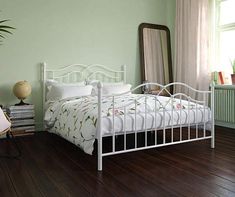 a white bed sitting on top of a hard wood floor next to a green wall