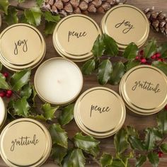 some candles are sitting next to holly and pine cones