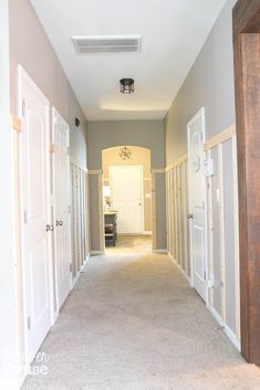 an empty hallway with white doors leading to another room