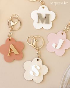 four different types of keychains with the letter m on one side and an initial on the other