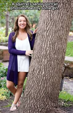 a woman standing next to a tree with her arms around the tree's trunk