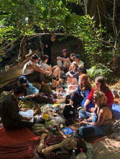 a group of people sitting on the ground in the woods