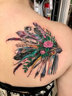 a woman's back with feathers and flowers on it