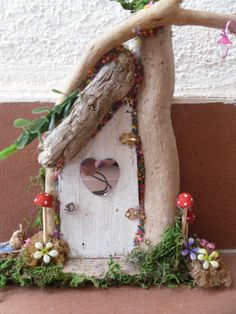 a bird house made out of driftwood with flowers and mushrooms on the outside wall