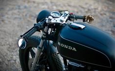 a black motorcycle parked on top of a gravel road