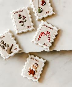 four decorated christmas cookies sitting on top of a white countertop next to candy canes