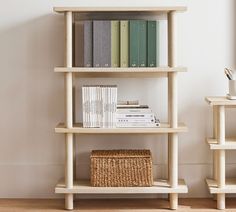 a bookshelf with several books on it next to a wicker basket and white walls