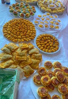 a table filled with lots of different types of food on white plates and serving trays