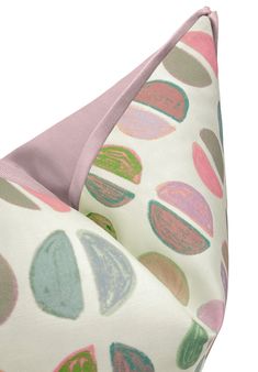 a pink and green polka dot print pillow on a white background, with the fabric folded over it