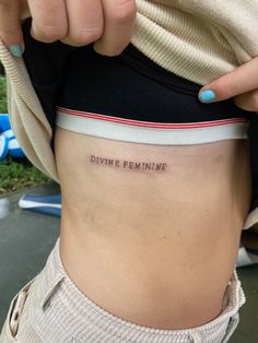 a woman's stomach with the words divine feminine written on it, in front of her