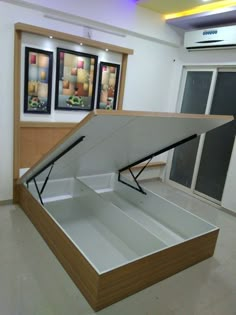 an open box sitting on top of a white floor in a room with pictures behind it