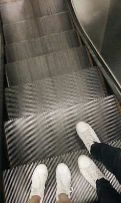 two people standing on an escalator with their feet up