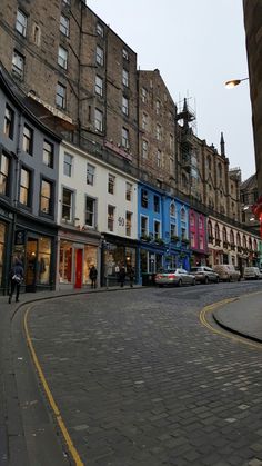 an empty street in the middle of a city with buildings on both sides and people walking around