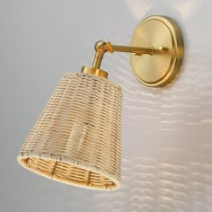 a wall light with a woven shade hanging from it's side on the wall