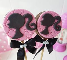 two pink and black decorated cookies sitting on top of each other