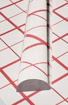 a roll of tape laying on top of a white and red tile floor next to a wall