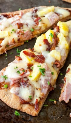 a pizza with pineapple, ham and cheese is cut into slices on a baking sheet