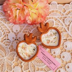 two heart shaped cookies sitting on top of a doily next to a pink flower