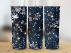 two blue tumbles with white snowflakes on them, sitting on a wooden table