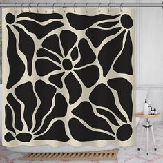 a black and white shower curtain with an abstract design in the center, on a bathroom floor