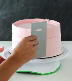 someone is cutting up a pink and grey cake