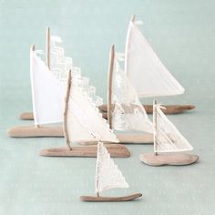 small wooden sailboats are sitting on the table with white lace and wood dows