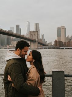 a man and woman standing next to each other near the water