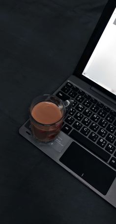 a cup of coffee sitting on top of a laptop computer