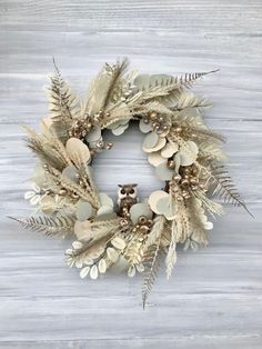 a wreath made out of dried leaves and feathers with an owl on it's head