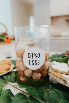 a table topped with lots of food next to a glass filled with nuts and crackers