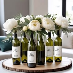 four bottles of wine with flowers in them on a wooden table next to a couch