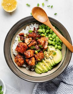 a bowl filled with rice, peas and chicken next to an avocado slice