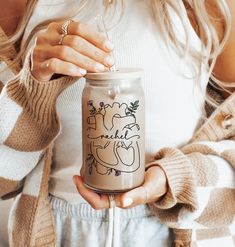 a woman holding a glass jar with a drawing on it