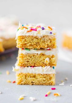 three pieces of cake with white frosting and sprinkles stacked on top of each other