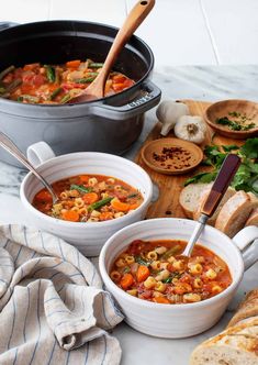 two bowls of vegetable soup with bread on the side