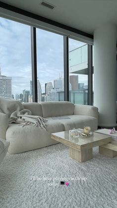 a living room filled with furniture next to large windows and a view of the city