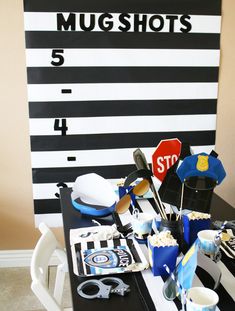 a table topped with lots of cupcakes next to a black and white striped wall