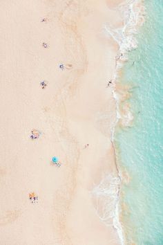 an aerial view of people laying on the beach and swimming in the water, from above