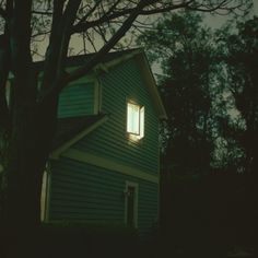 a house with a tree in front of it and the light coming through the window