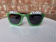 These custom order Men's Ray Ban Style Sunnies 🕶️ are the perfect accessory for any event where you need a little flair! Make great gifts for a wedding party. Enjoy these custom and one-of-a-kind sunglasses that include lots sparkles ✨ and whatever phrase and colors your order!  Each pair of bejeweled beauties comes wrapped up tight. I am happy to make custom pairs! Please contact me if you want a different word or color combo! Please note that due to the unique nature of these sunglasses, no t Bedazzled Sunglasses, Wedding Party Gift, Man Ray, Unique Nature, Green Gems, Mens Style, Gifts For Wedding Party, Color Combo, Men's Style