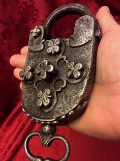 a hand holding an old metal lock with flowers on it's side and a heart in the middle