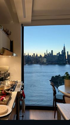 a kitchen with a view of the water and buildings in the distance is seen from across the room