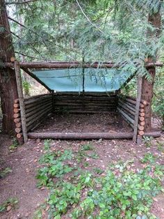 an outdoor shelter made out of logs in the woods