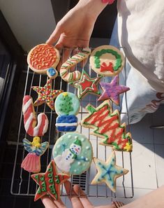 someone is holding up some decorated cookies on a rack