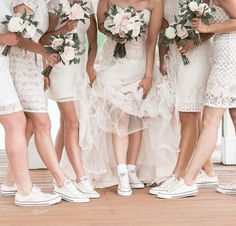 a group of women standing next to each other wearing white shoes and dresses with flowers on them