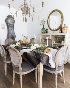 a dining room table set for four with candles and plates on top of the table