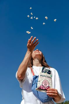 a woman holding a book in front of her face as she looks up into the sky